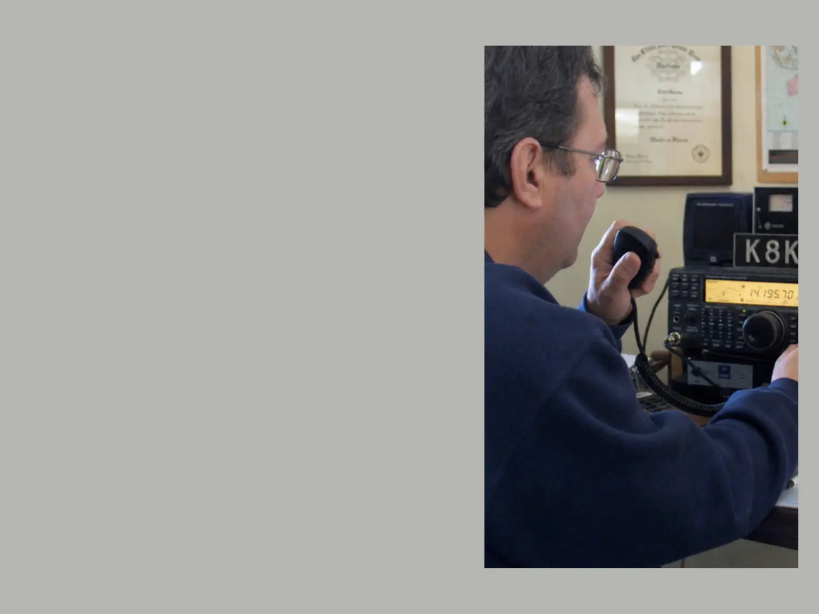 Amateur radio operator using an HF transceiver with an analog S-meter in a home radio shack.