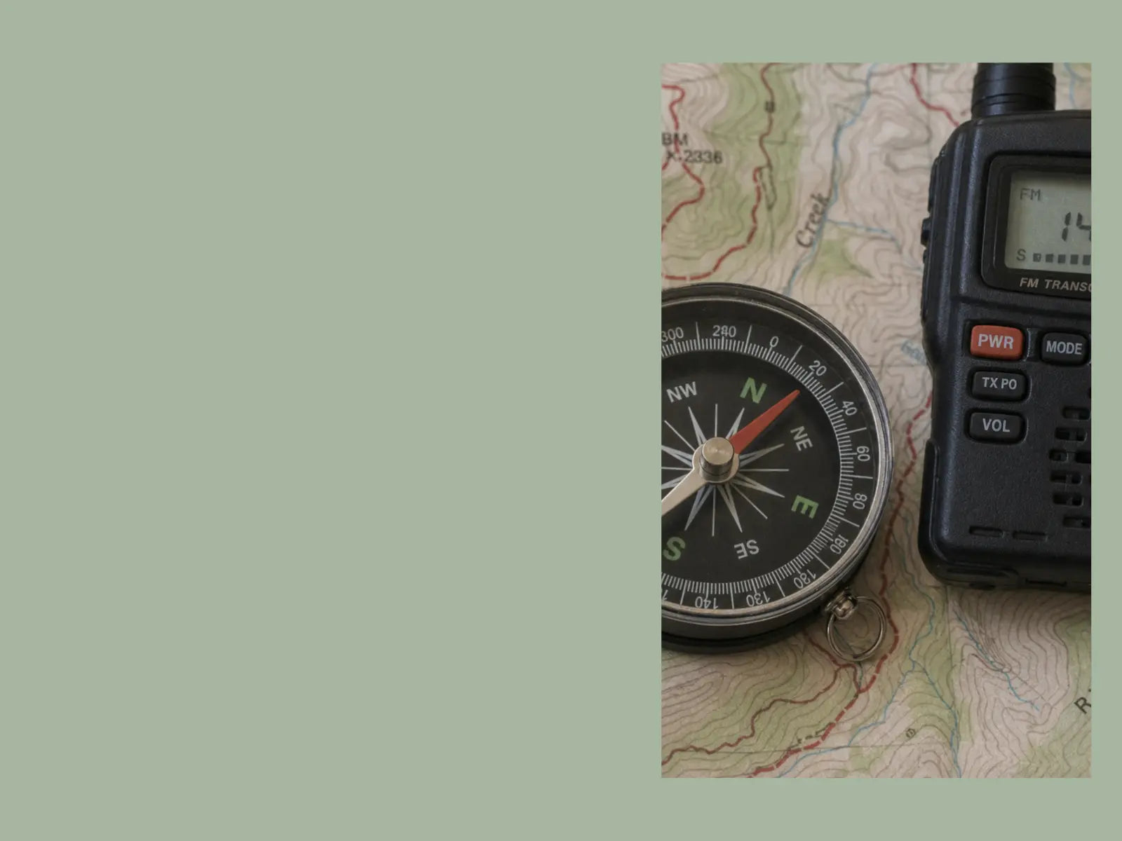 A magnetic compass on a topographic map beside a portable amateur radio transceiver