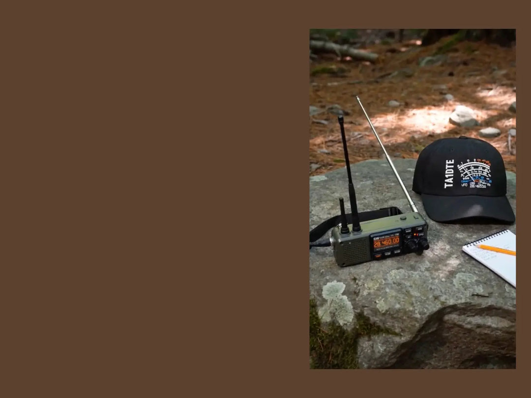 A black Richardson-112 cap with a white 'TA1DTE' callsign and S meter graphic, next to a vintage radio receiver with two antennas on a stone outdoors, with a notebook nearby.