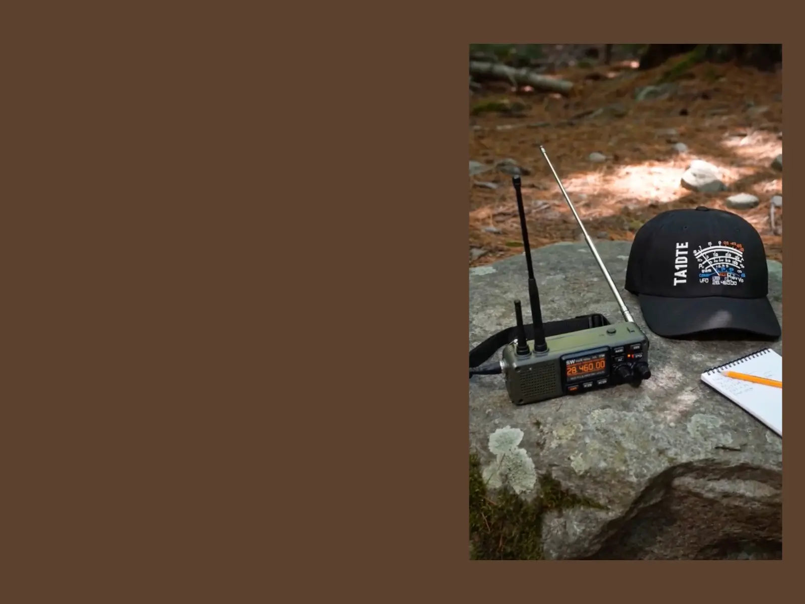 A black Richardson-112 cap with a white 'TA1DTE' callsign and S meter graphic, next to a vintage radio receiver with two antennas on a stone outdoors, with a notebook nearby.