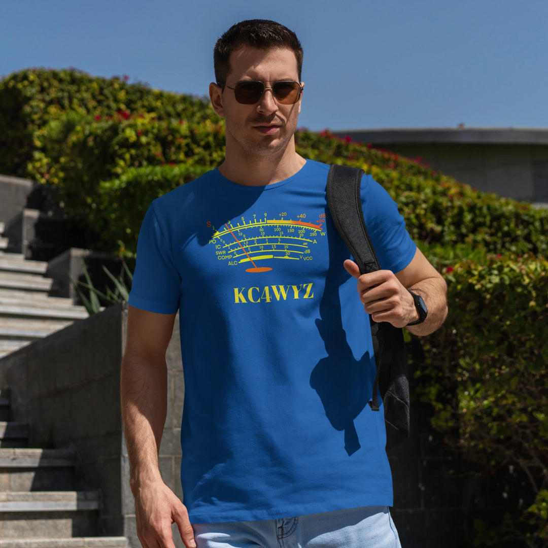 A man wearing a bright blue ham radio S meter graphic t-shirt and the text 'KC4WYZ' printed on the chest, standing outdoors in front of green bushes and concrete steps.