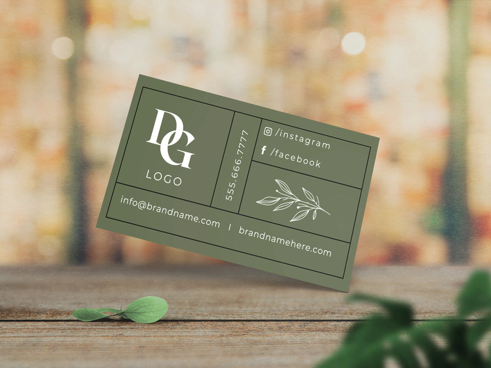 Green business card with branding details on a wooden surface with blurred natural background