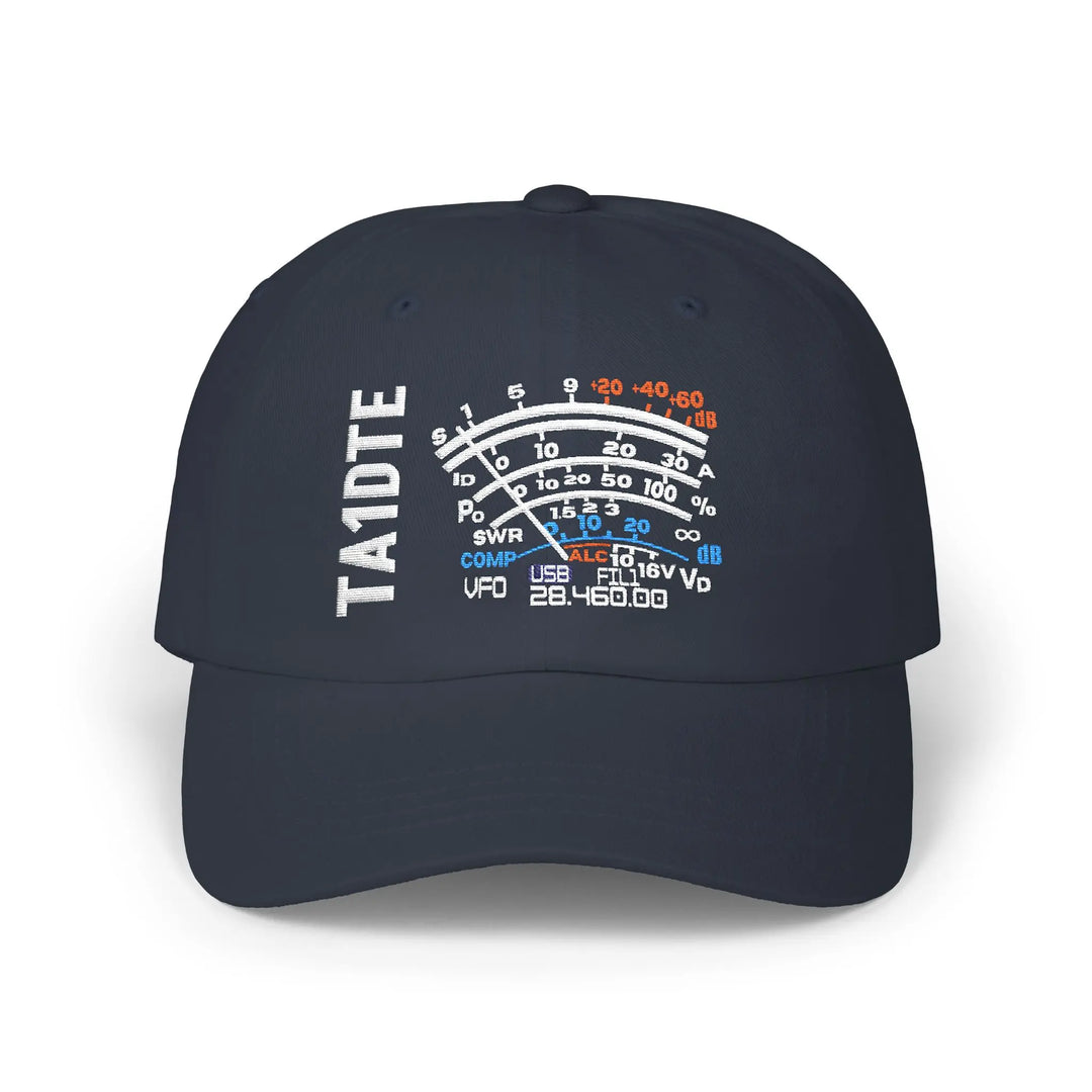 A navy blue baseball cap featuring a white, blue, and orange graphic on the front that resembles a vintage radio S meter graphic with the text 'TA1DTE' embroidered vertically on the left side of the graphic.